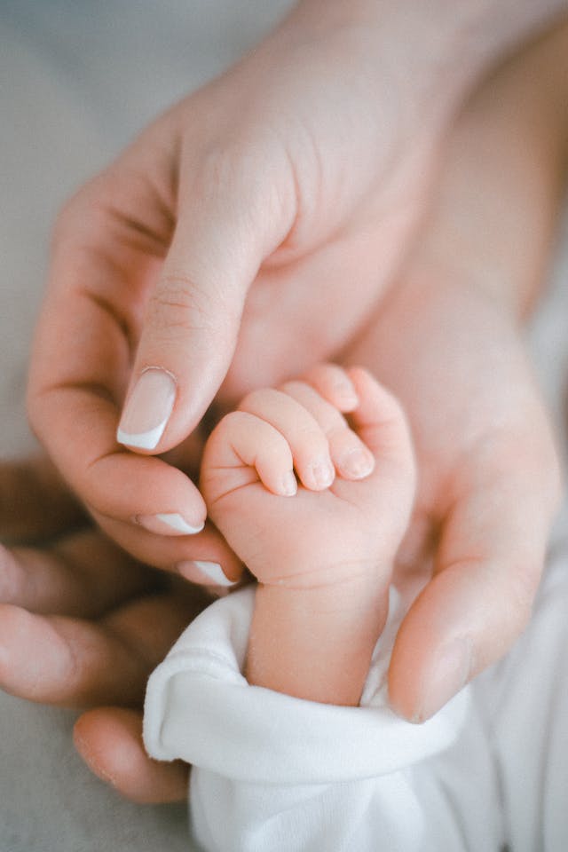 A mother holds her baby's hand at a naming ceremony.